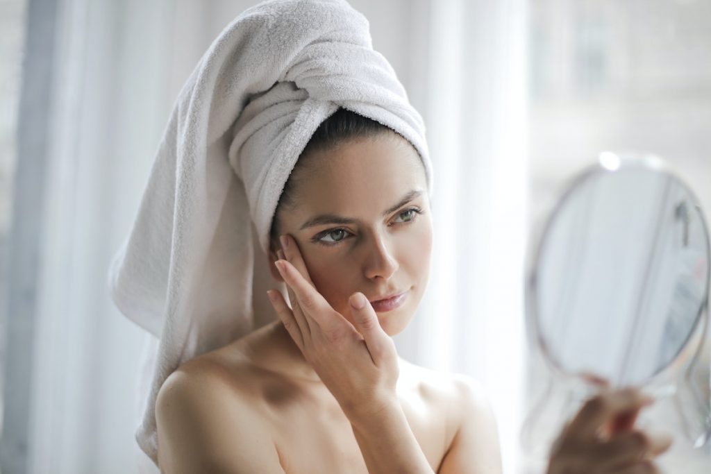 Tender woman after shower examining skin with mirror
