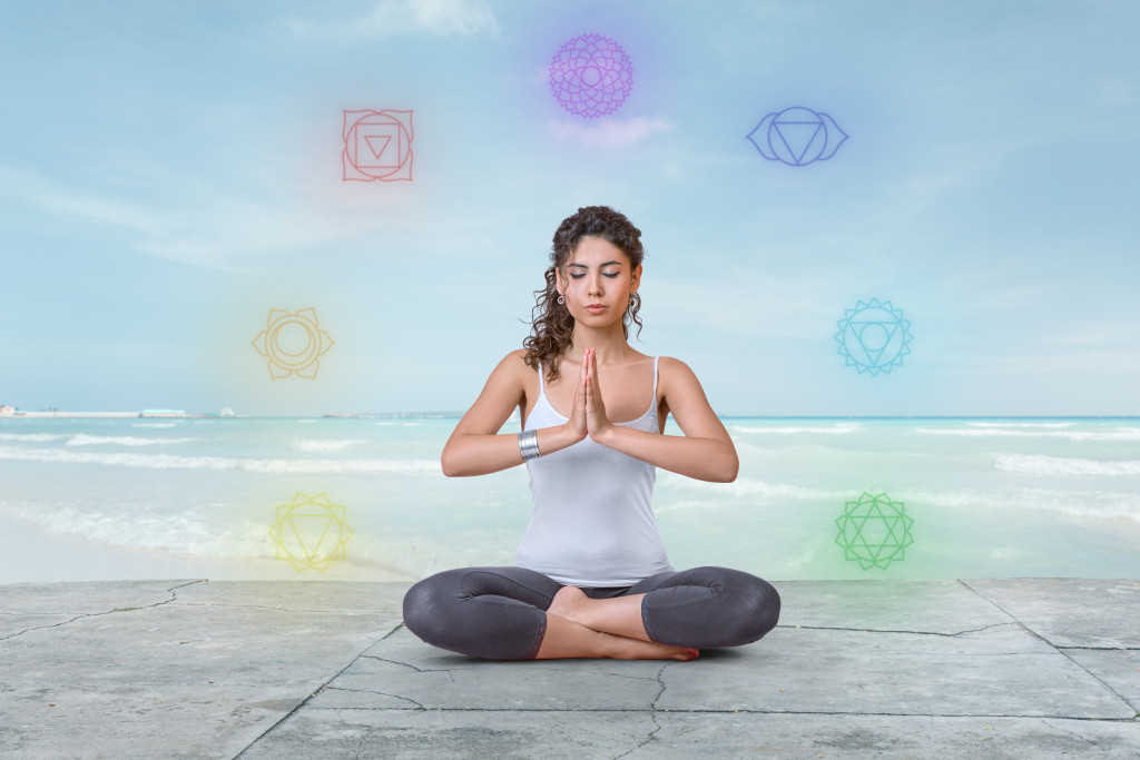 A young woman meditating with chakras around her