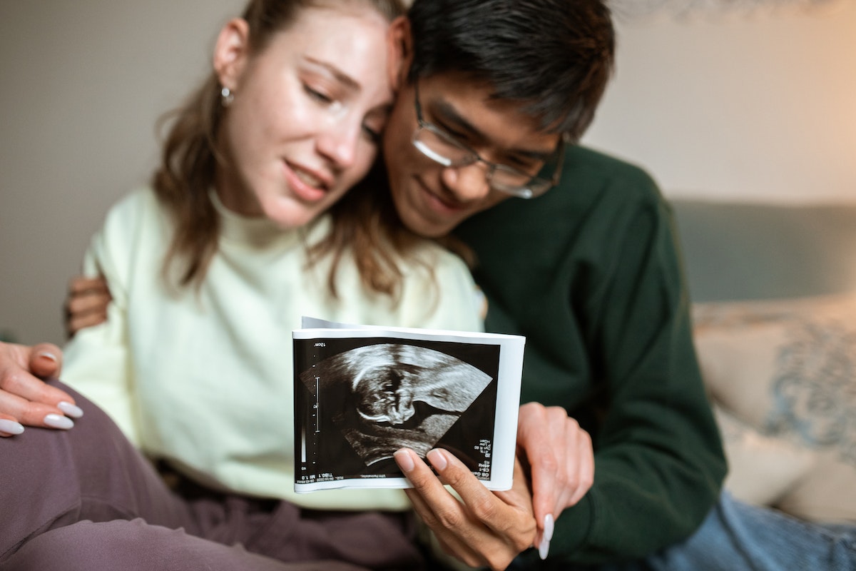 happy pregnant woman with her husband holding a copy of their baby's ultrasound