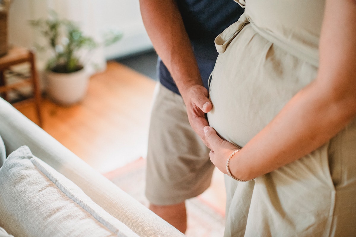 husband gently holding his wife's tummy because she is pregnant