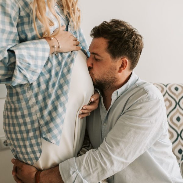 husband kissing his wife's tummy because she is pregnant