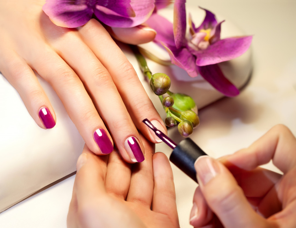 woman getting her nails done in pink purple color