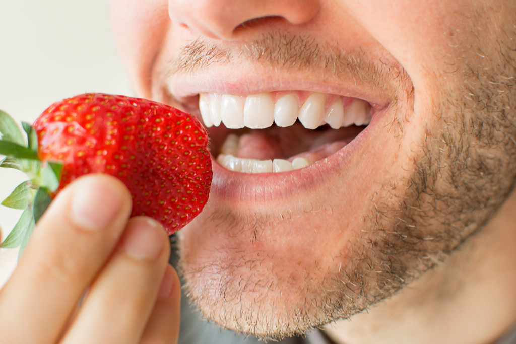 man eating a strawberry smiling closeup