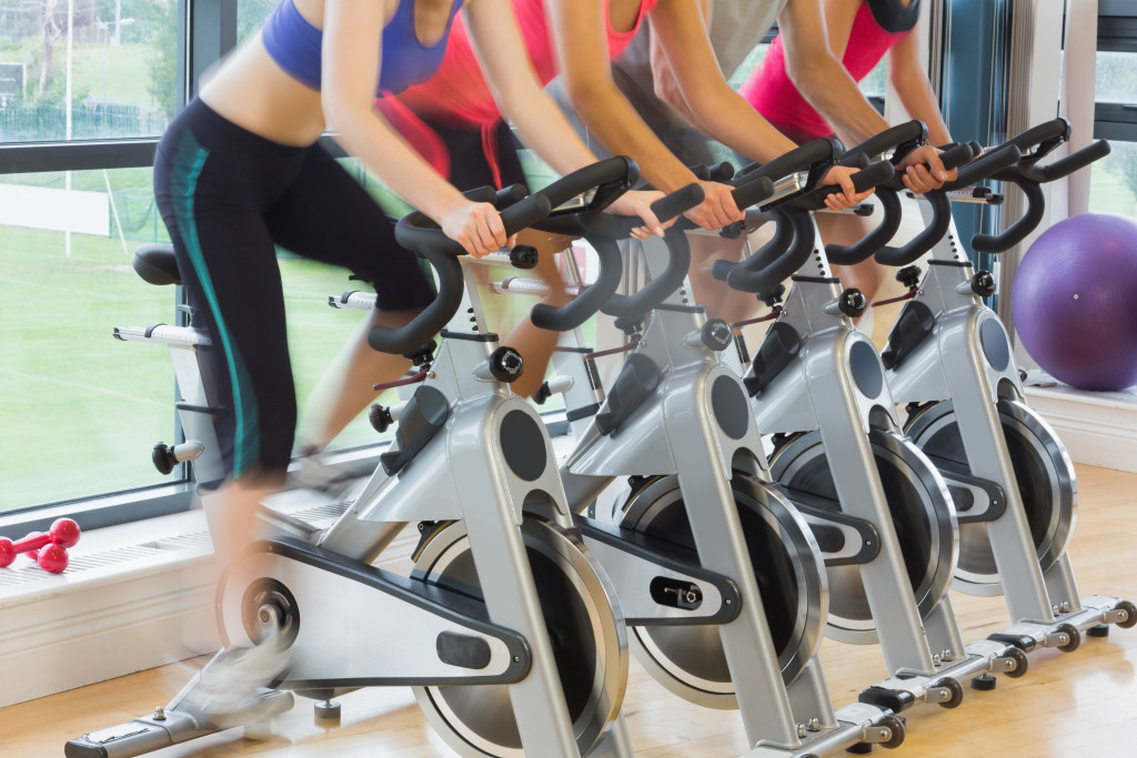 Group of people exercising at a gym using a stationary bike.